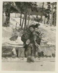 Image of Dr. Langford sitting on sledge in front of house
